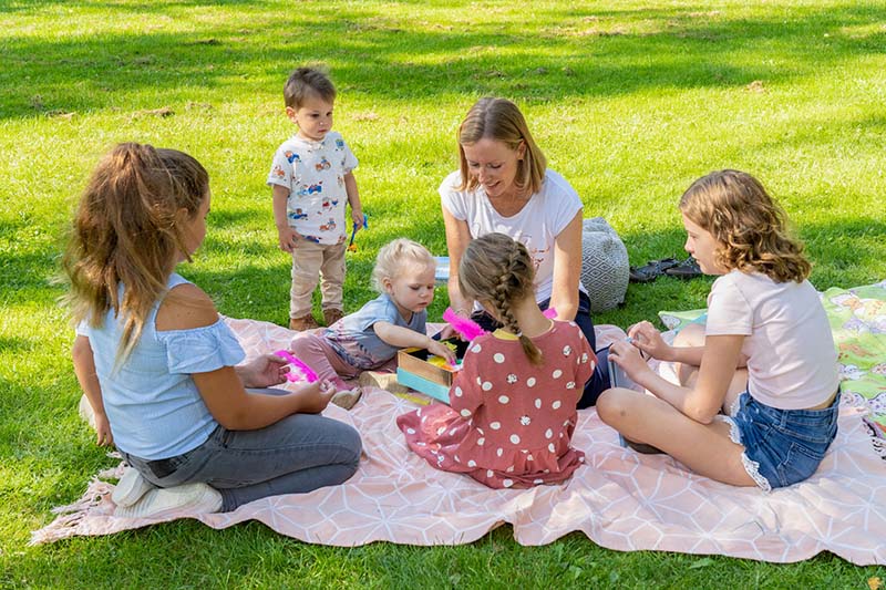 Margit mit Kindern auf Picknickdecke im Grünen